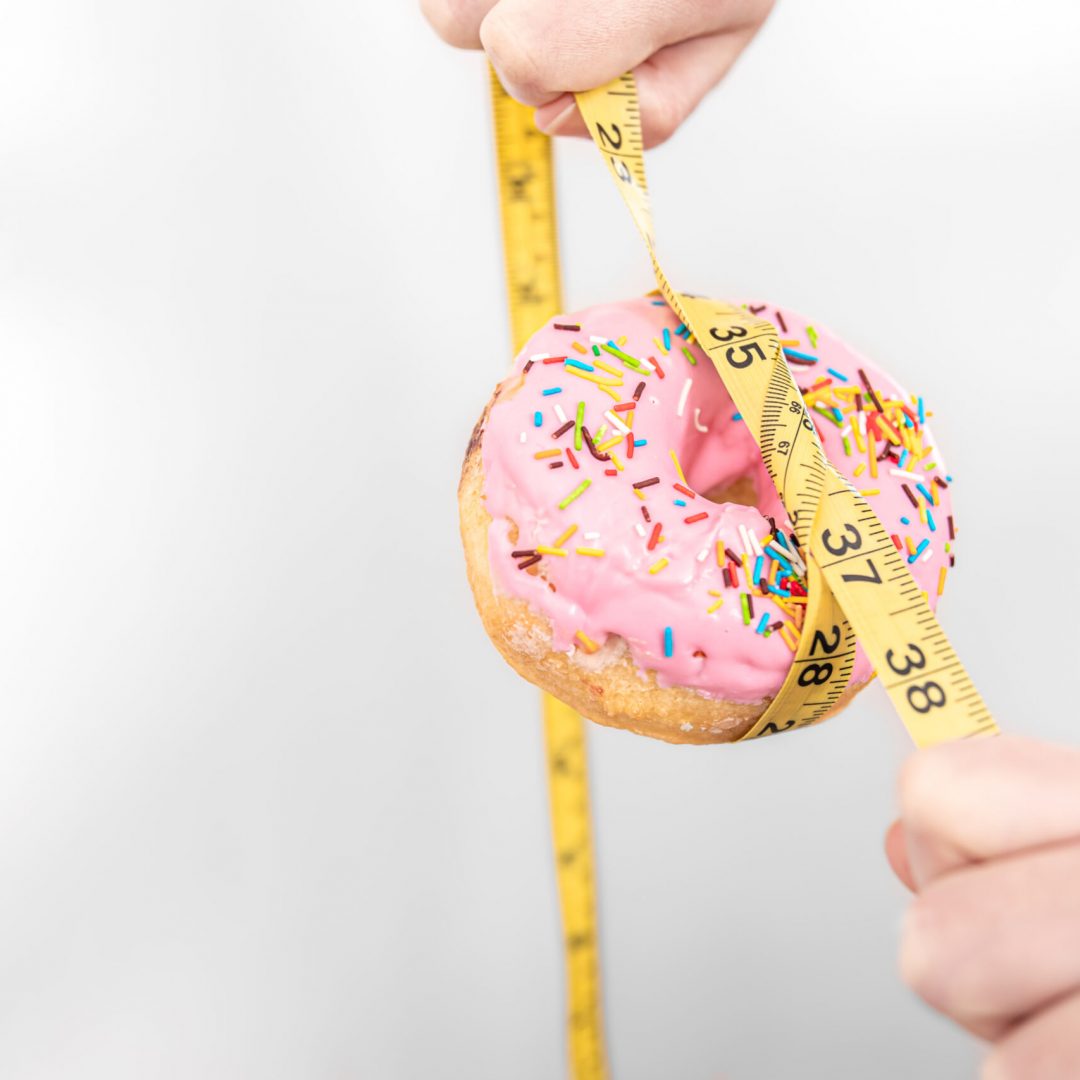 close-up-donut-measuring-tape-weight-loss-diet-concept-copy-space-1-scaled.jpg